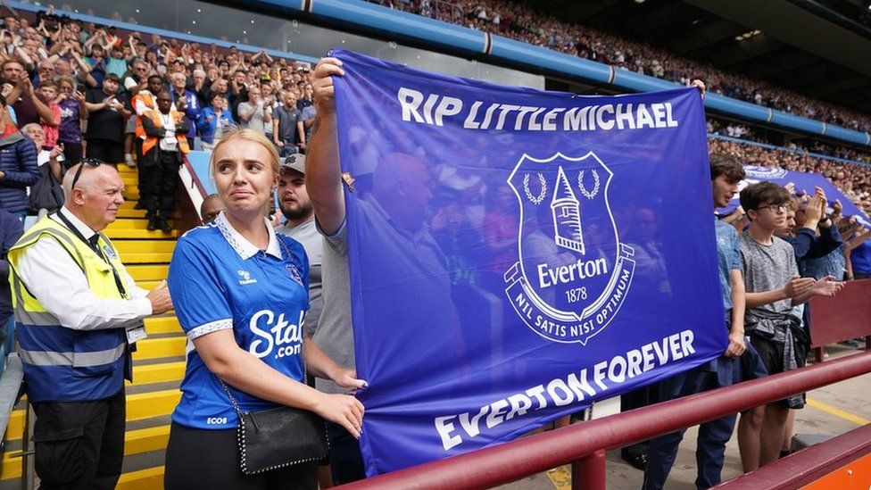 Fans hold up a flag in honour of construction worker Michael Jones baring the message: 'RIP Little Michael, Everton Forever.'