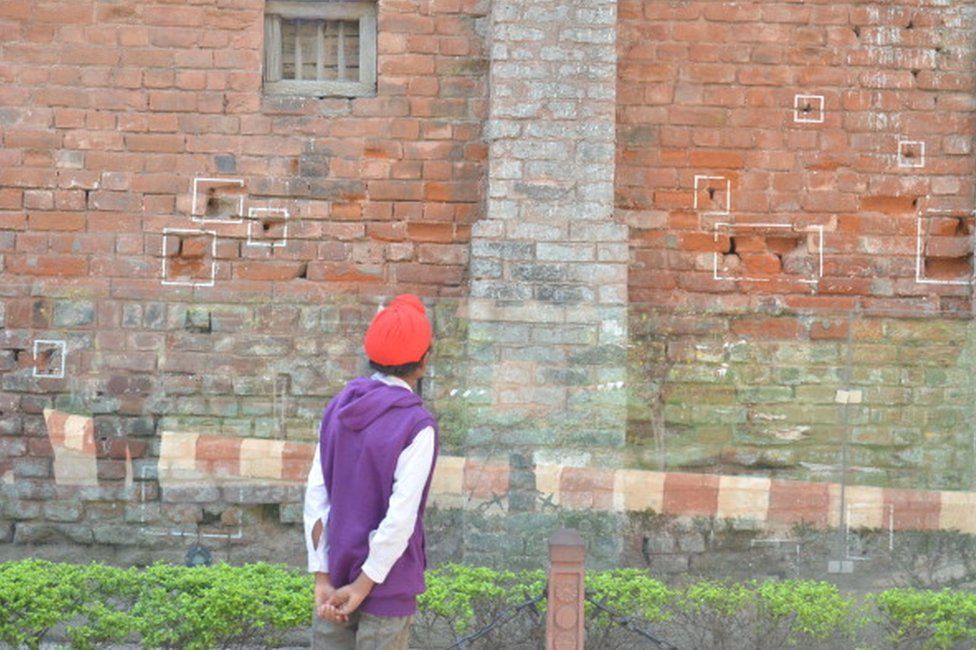 A visitor looking at the bullet marks on a wall on the eve of 95th anniversary of the massacre at Jallianwala Bagh on 12 April 2014 in Amritsar.