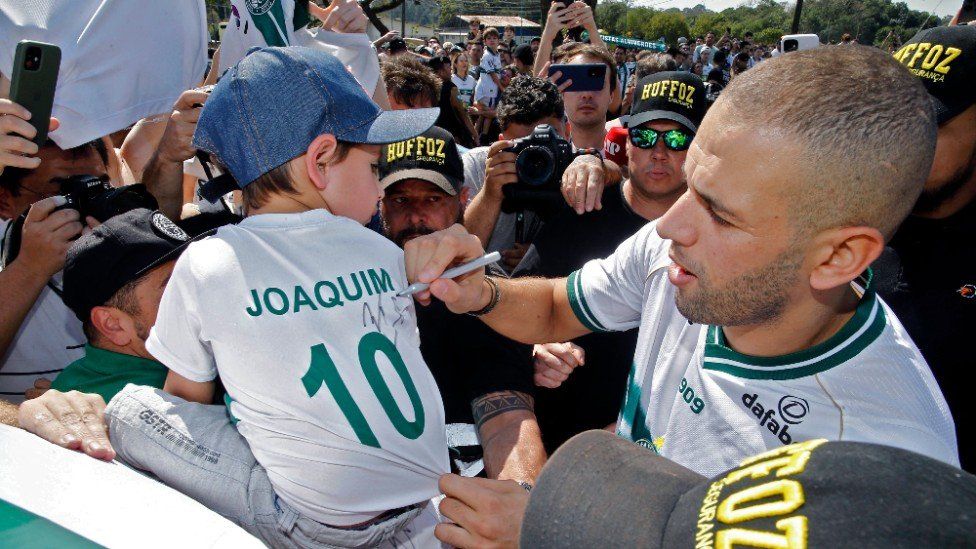 Forward Islam Slimani, Algeria's all-time leading scorer, signs a jersey as he is welcomed by supporters of his new football team Coritiba.
