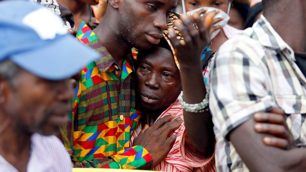 Woman is comforted after learning she has lost her son, in Freetown, on 16 August 2017