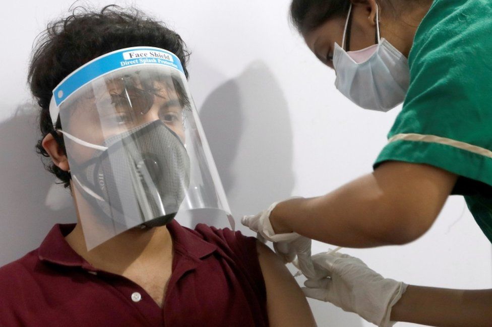 A man wearing a face shield gets a dose of the Covishield vaccine at a vaccination centre in Mumbai, India, May 1, 2021.