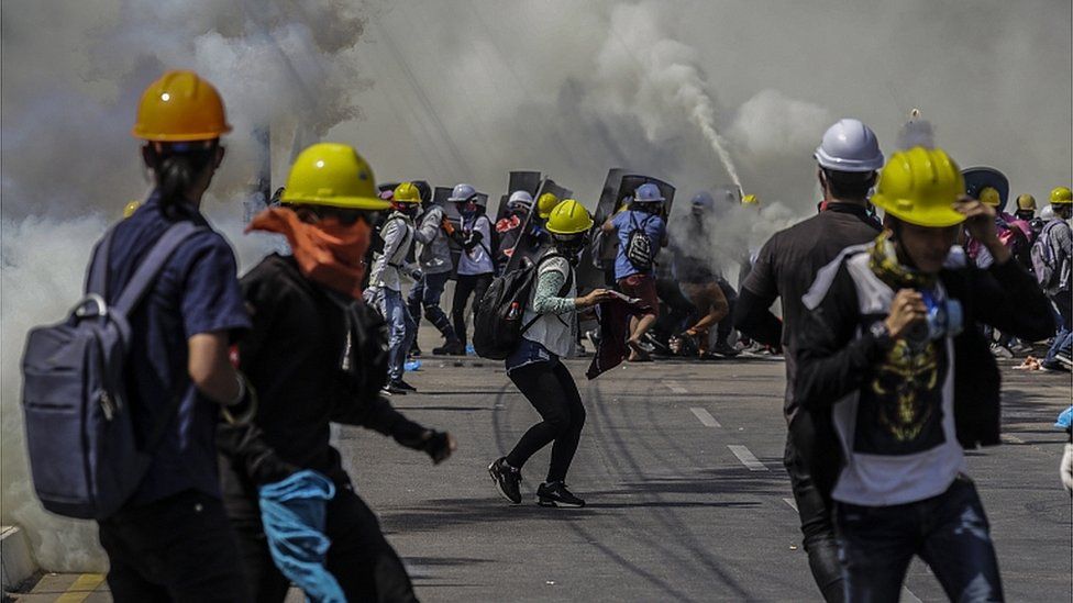 Демонстранты реагируют на слезоточивый газ, применяемый полицией во время акции протеста против военного переворота в Янгоне, Мьянма, 6 марта 2021 г.