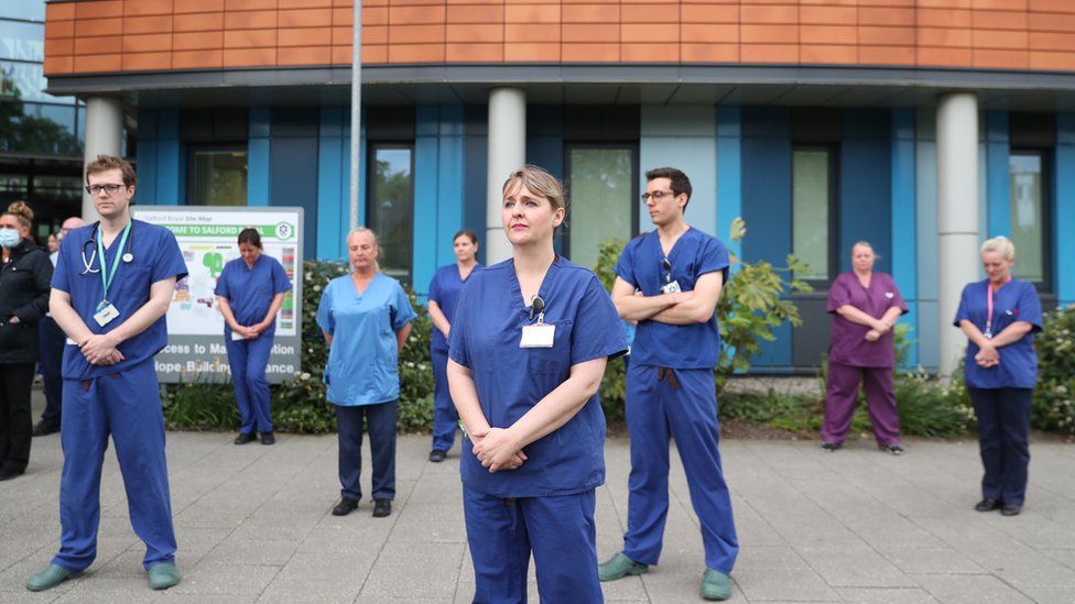Staff stand outside Salford Royal Hospital in Manchester during a minute"s silence to pay tribute to the NHS staff and key workers who have died during the coronavirus outbreak.