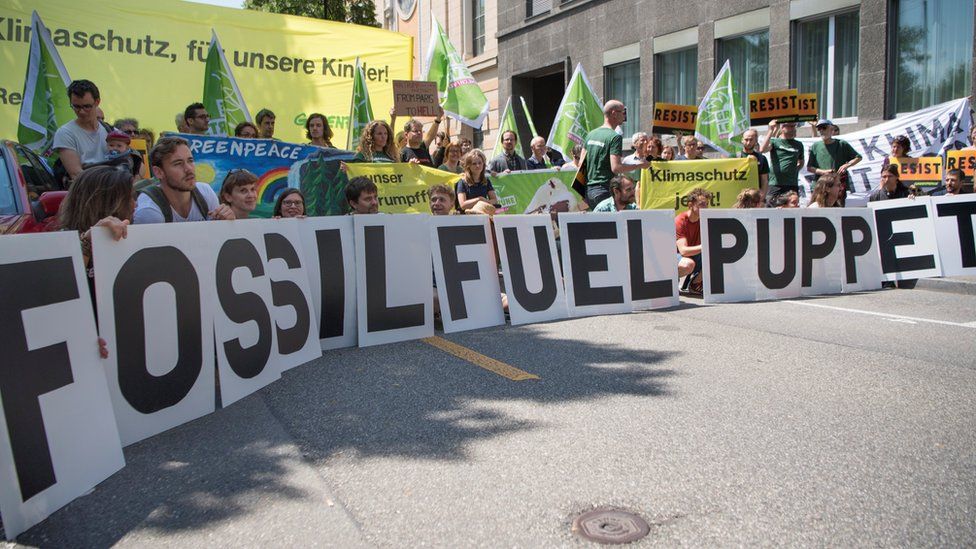 Activists of Greenpeace protest with a sign reading "fossil fuel puppet" in front of the US embassy in Bern, 2 June