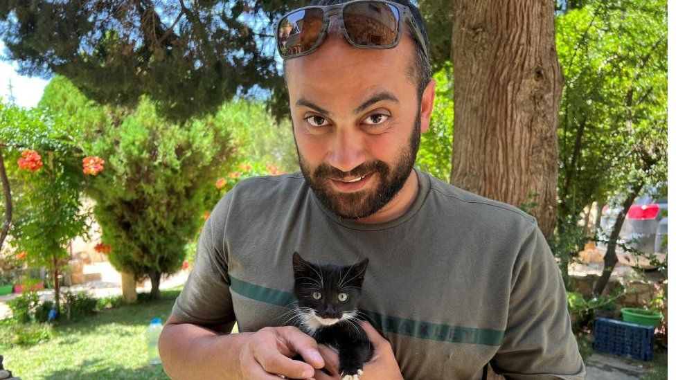 Reuters visuals journalist Issam Abdallah holds a kitten while posing for a picture in Saaideh, Lebanon