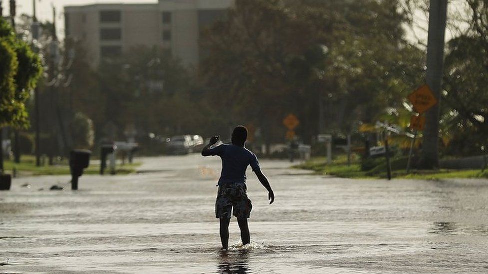 A teen walks through flooded streets the morning after Hurricane Irma swept through the area on September 11, 2017 in Naples, Florida