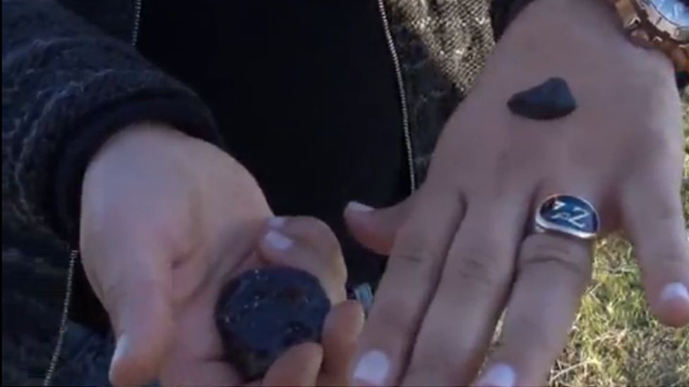 A woman's hands holding small meteorite pieces