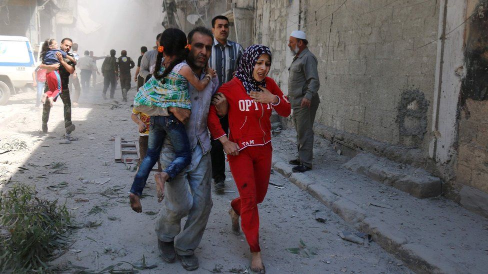 Syrians run for cover following a reported air strike on the rebel-held district of Qatarji, Aleppo (29 April 2016)