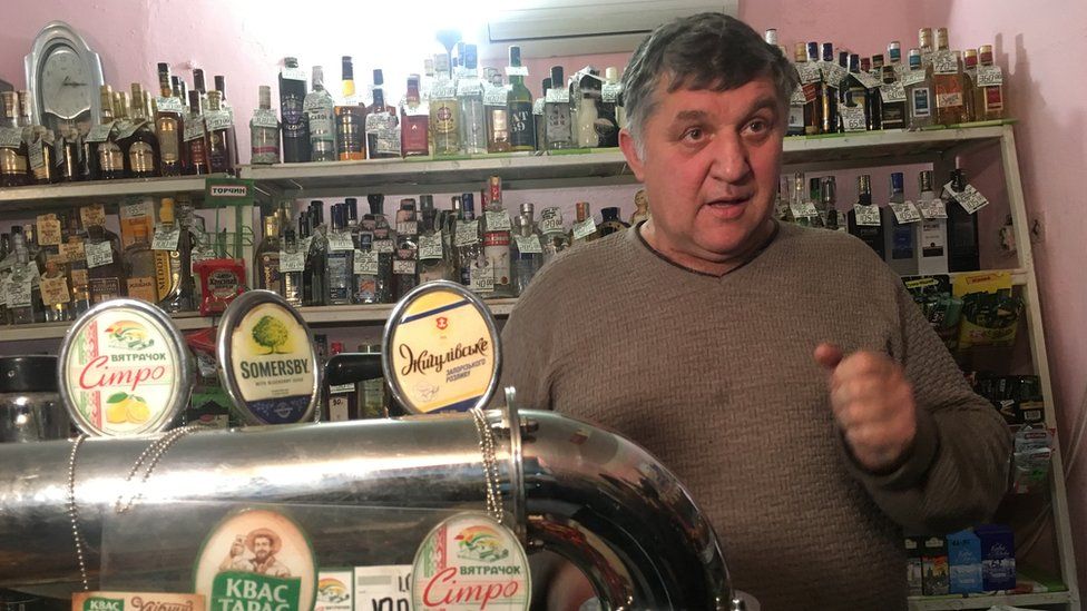 Shop owner Viktor speaking to the BBC in front of a bar