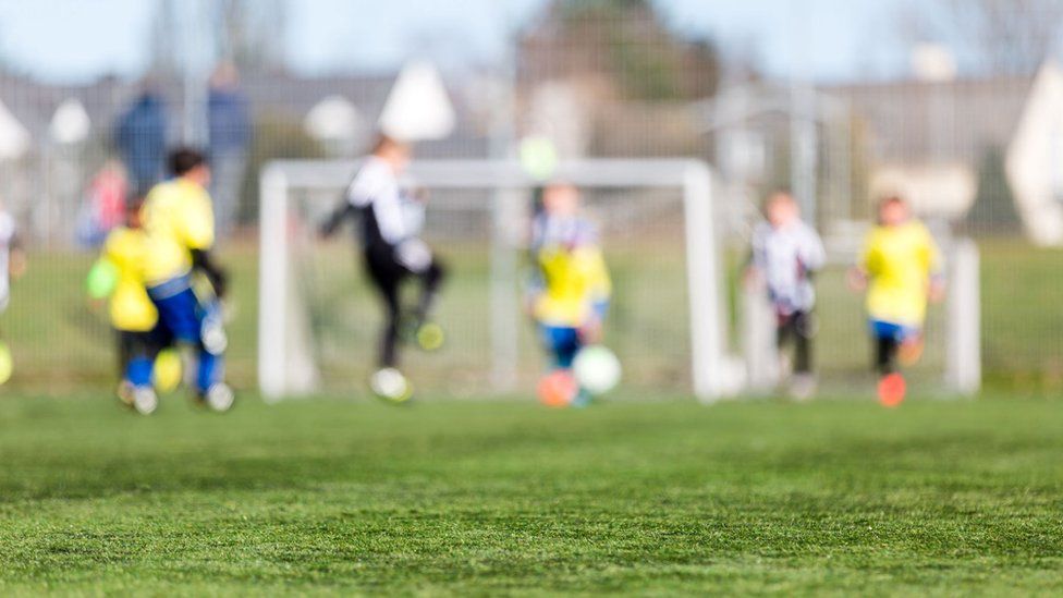 Blurred image of young kids playing a youth soccer match outdoors on an green soccer pitch