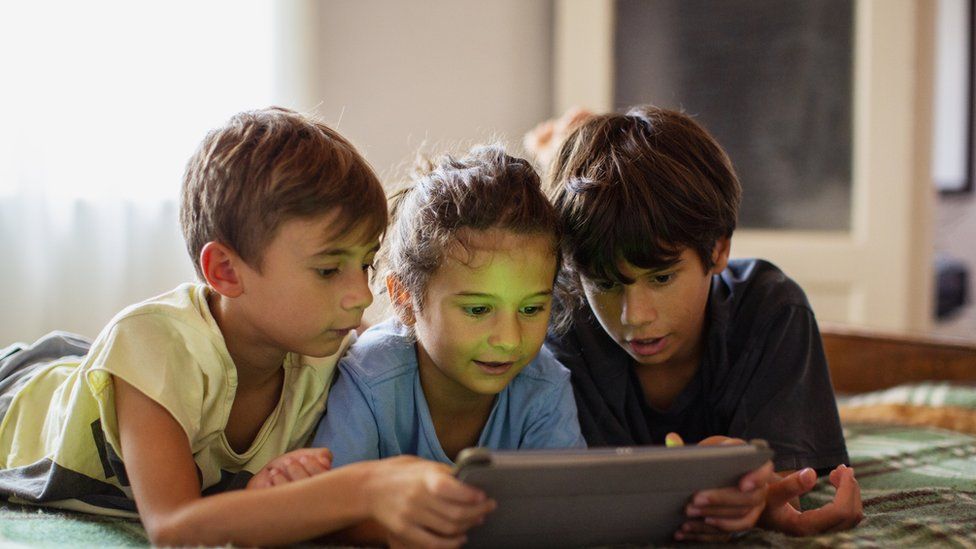 Children huddled together looking at a tablet screen