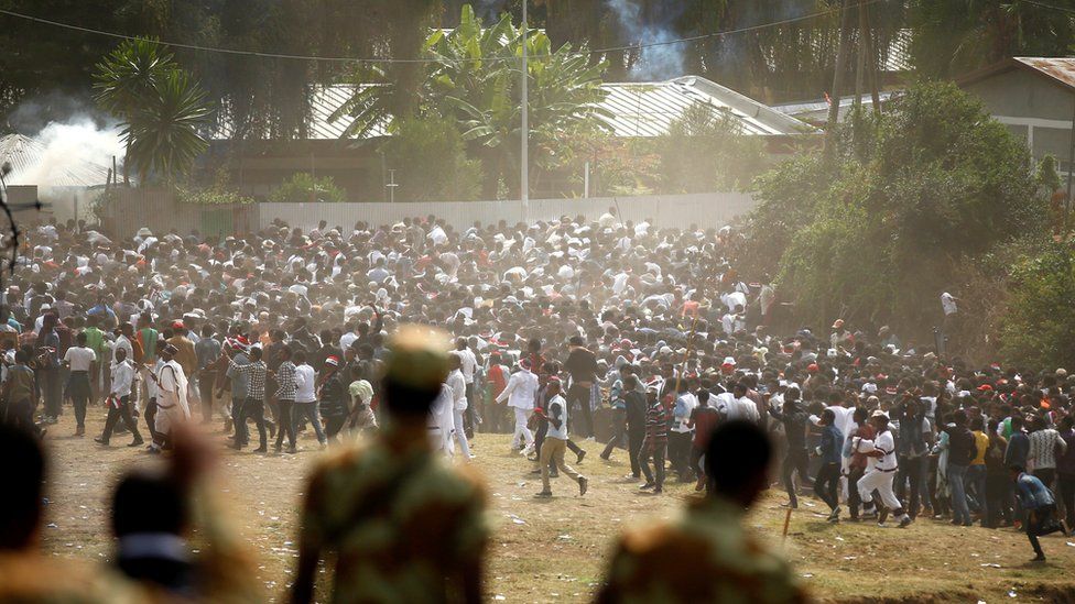 Soldiers watch protestors run from tear gas during a festival in Oromia, October 2, 2016
