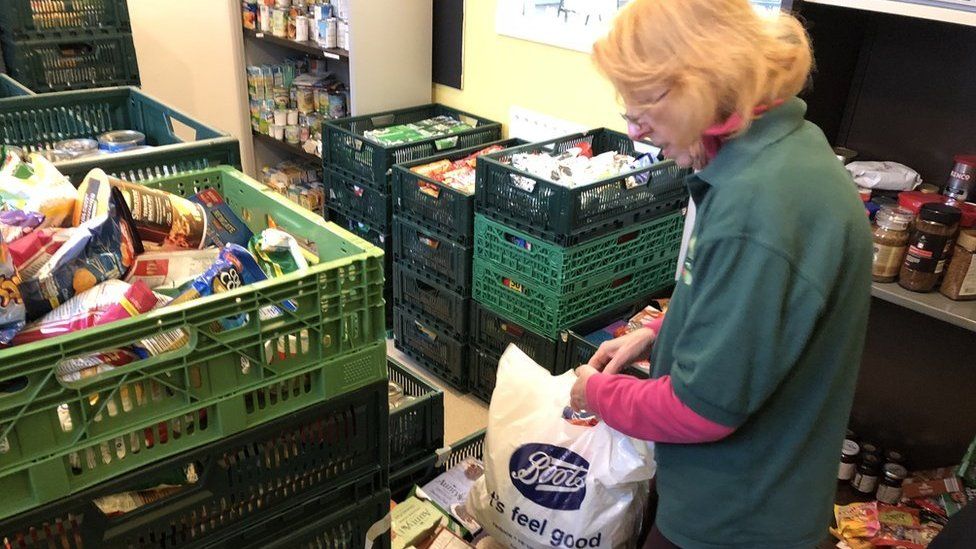 A volunteer filling a bag with food