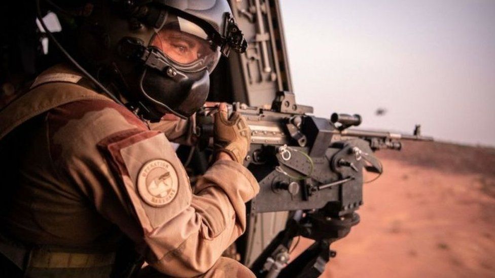 Ein Soldat der Barkhane-Streitkräfte hält eine Waffe in einem Hubschrauber, während er im Juli 2022 während eines offiziellen Besuchs der französischen Außen- und Streitkräfteminister in Niger in der Nähe der Militärbasis Ouallam fliegt.