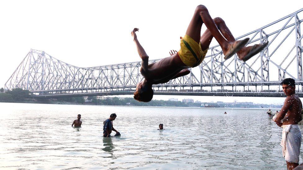 A boy jumps into the Ganges River to cool off