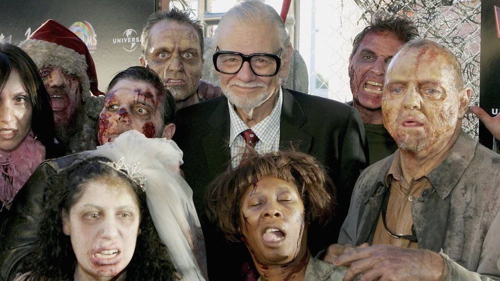 Director George A. Romero is surrounded by actors portraying zombies as he arrives for the world premiere of his movie 'Land of the Dead' in 2005