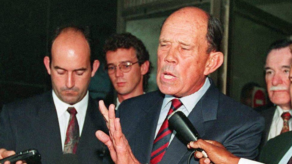 A picture taken on November 2, 1995 shows former South African military General Magnus Malan telling journalists that 'this is the darkest South African democracy and biggest concern ever to freedom of South Africa,' outside Durban's regional court, where Malan and 10 other generals appeared briefly over their alleged involvement in the 1987 massacre of 13 people in KwaMakhutha, south of Durban