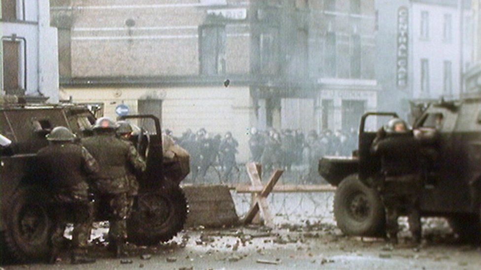 Soldiers stand behind armoured vehicles during violence in Londonderry
