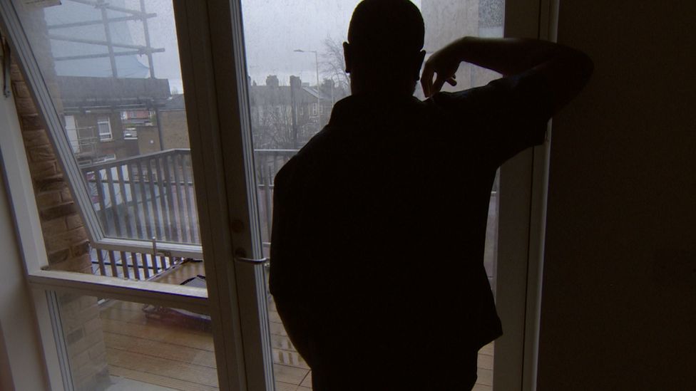 The anonymous resident stands with his back to the camera looking out over his damaged balcony