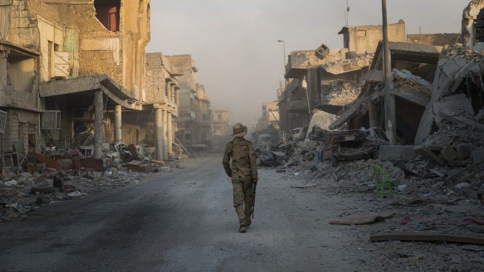 Person walking through ruined street in Mosul, Iraq