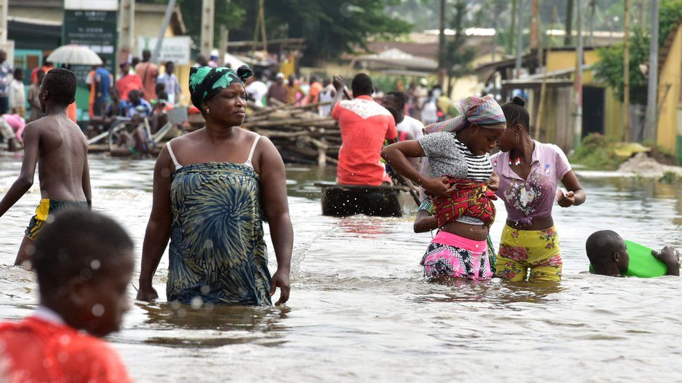 People wade through water in Aboisso, Ivory Coast - Saturday 14 July 2018