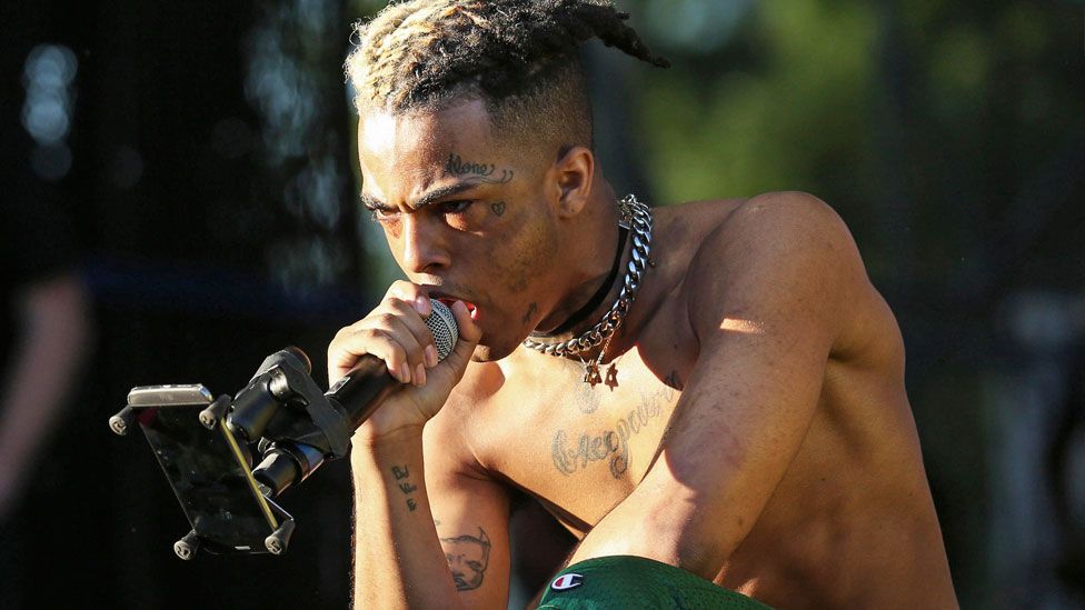 XXXTentacion performing on stage topless at outdoor event