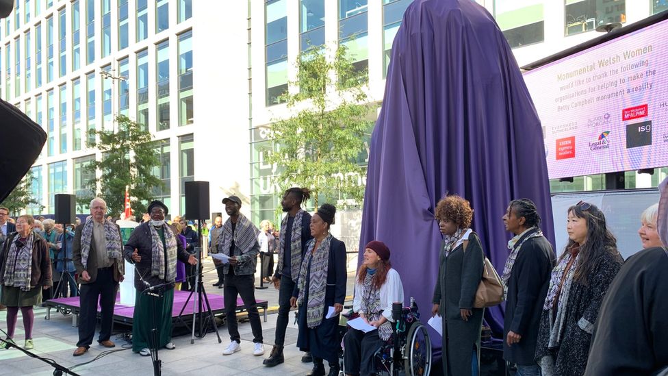 A choir singing next to the veiled statue