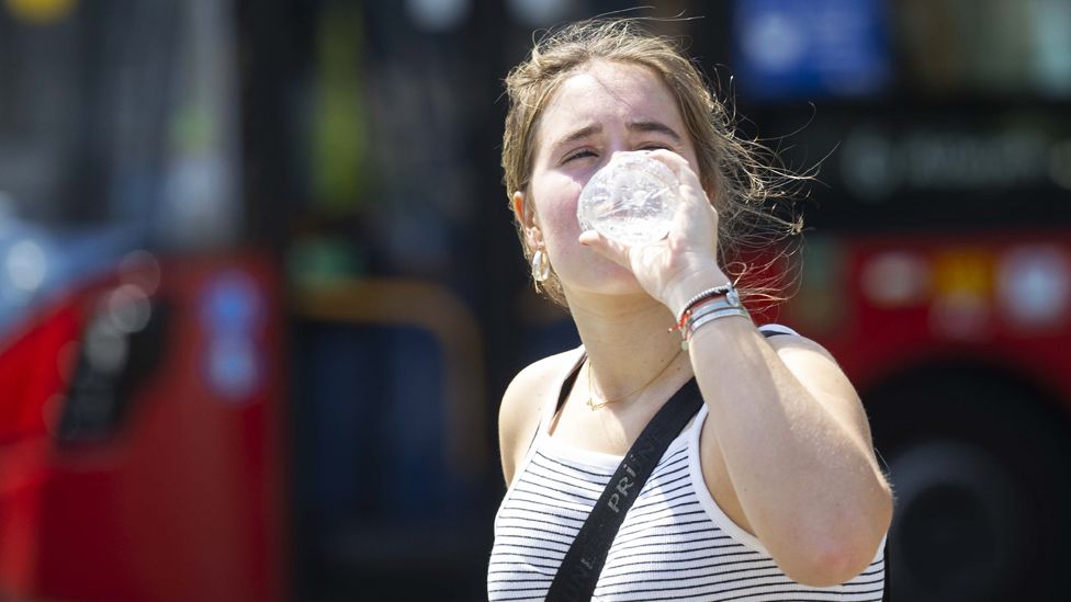 Женщина пьет воду, чтобы остыть во время сильной жары в Лондоне, Великобритания, 19 июля 202 г.