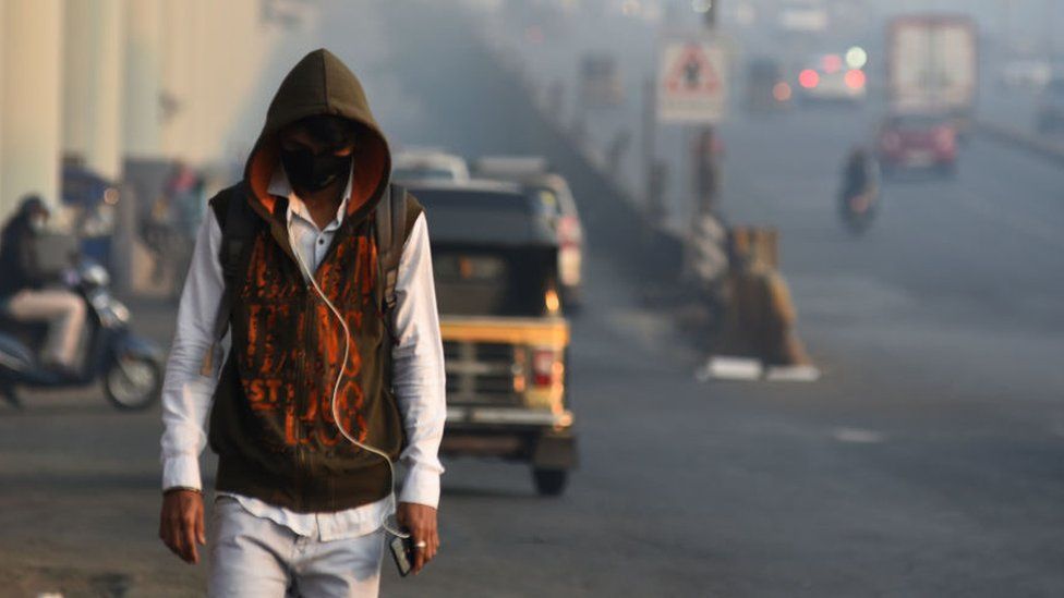 Люди гуляют утром в холодную и задымленную погоду в Горегаоне, 11 января 2022 года в Мумбаи, Индия