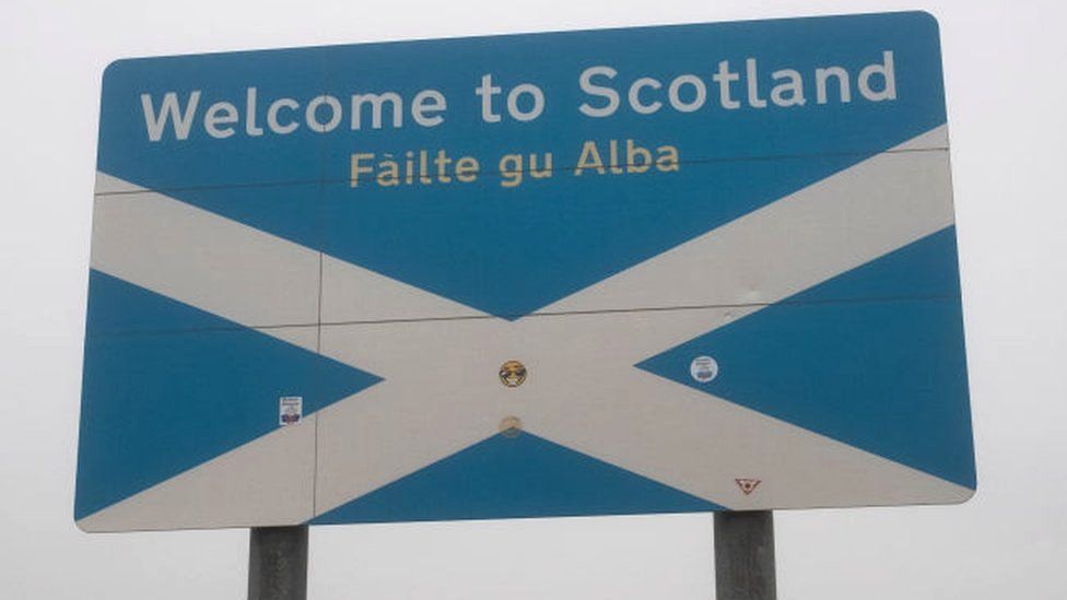 A Welcome to Scotland sign and Scottish flag on the Scottish side of the border with England