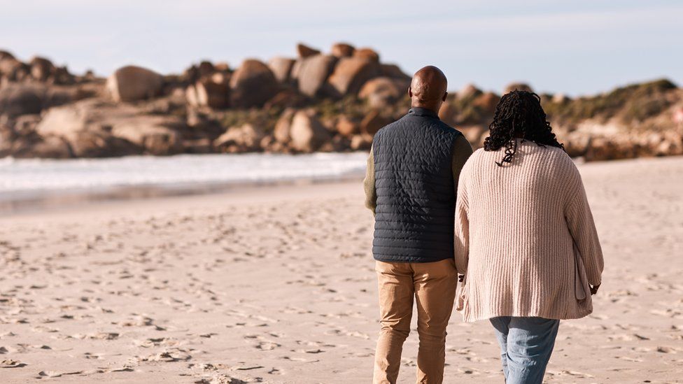 A couple walk along a beach together