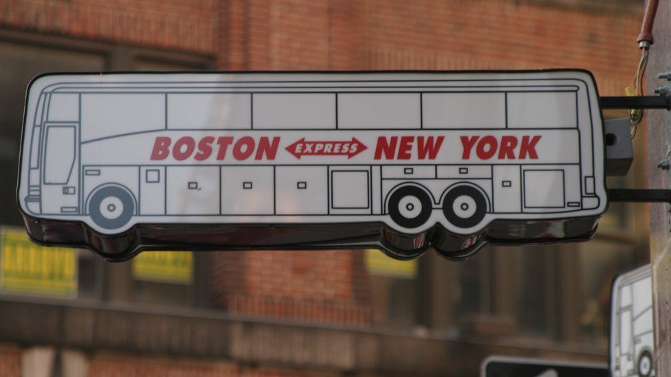 A sign advertising bus services between Boston and New York