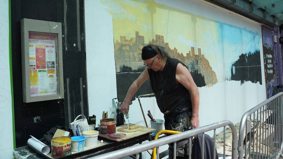 An artist rolling paint onto a roller