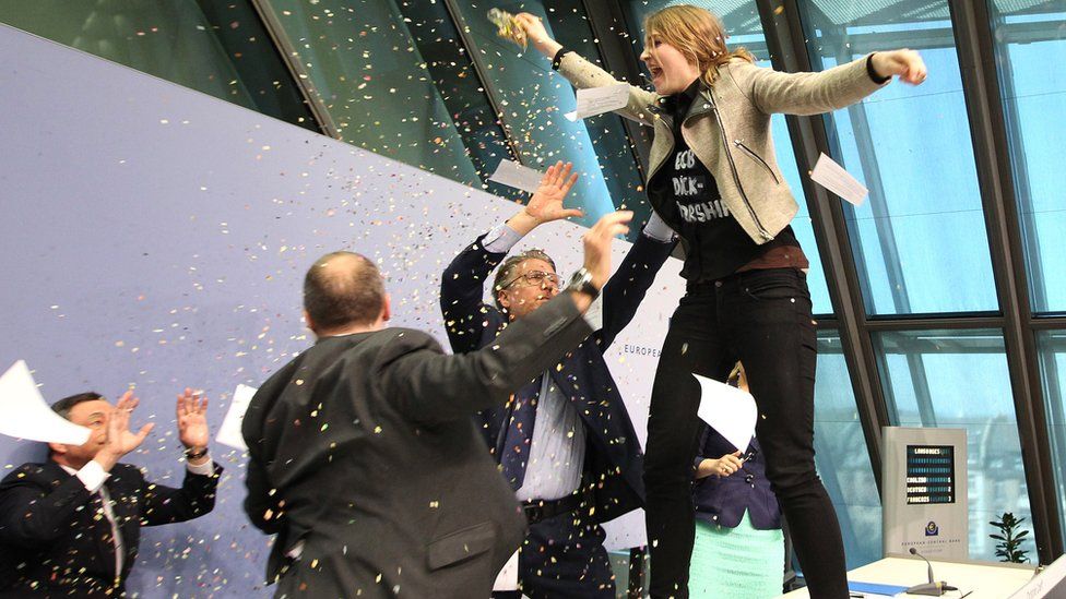 A woman disrupts a press conference by Mario Draghi (L), president of the European Central Bank by throwing confetti and calling for an 'end to the ECB dictatorship', 15 April 15, 2015