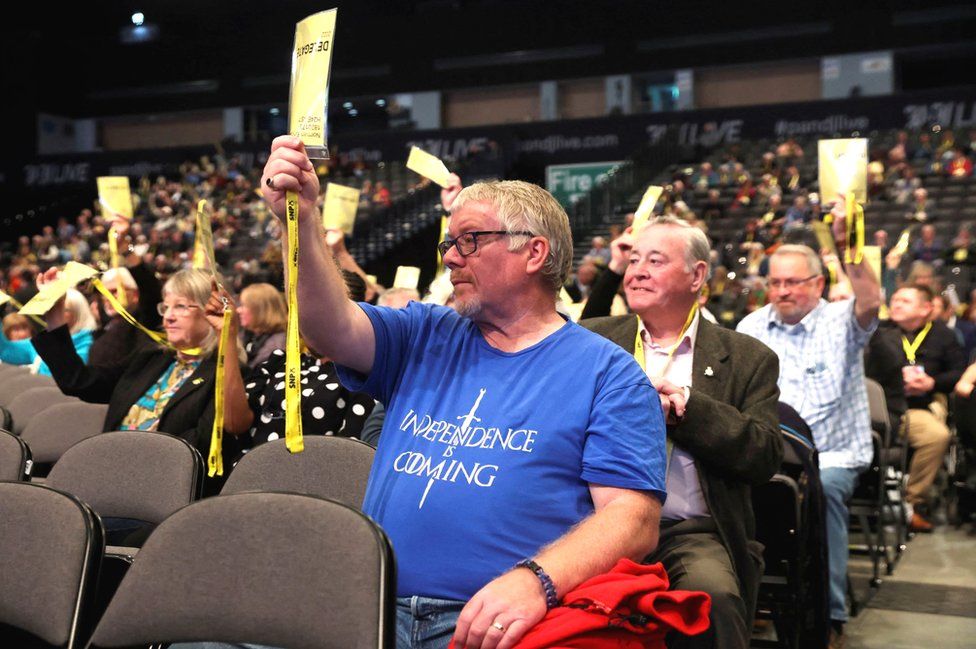 Man holds up his accreditation at the SNP conference