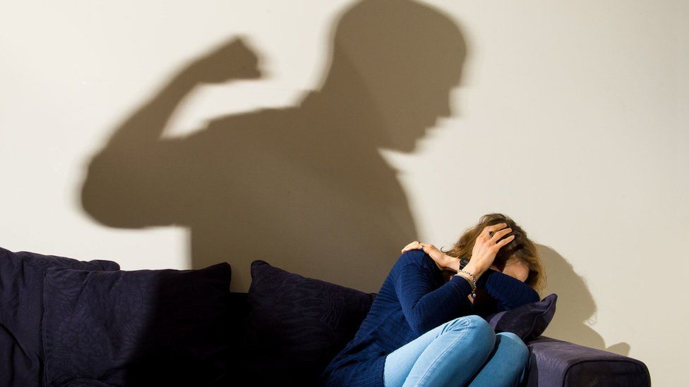 Generic image suggesting domestic violence with a shadow of a man raising his fist behind a woman cowering on a sofa