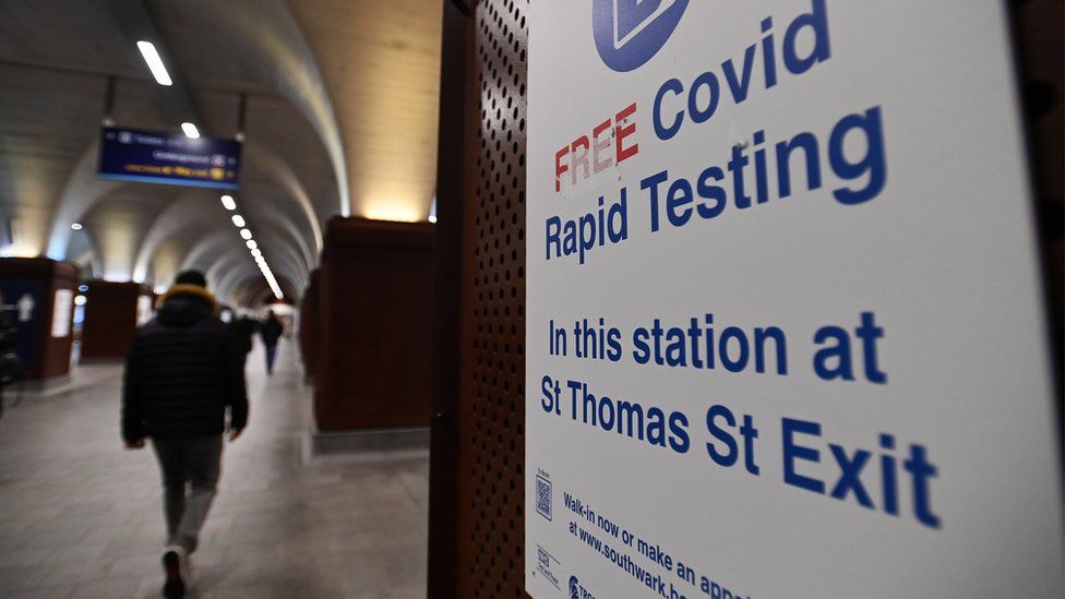 Man walks past Covid testing sign in railway station