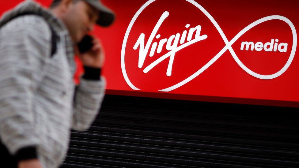 Мужчина проходит мимо магазина с логотипом Virgin Media