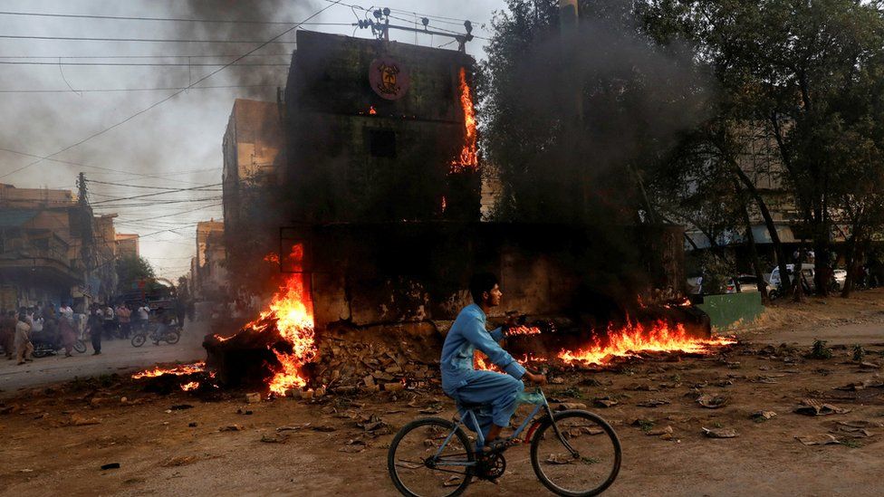 A boy rides past a paramilitary check post, that was set afire by the supporters of Pakistan's former Prime Minister Imran Khan, during a protest against his arrest, in Karachi,