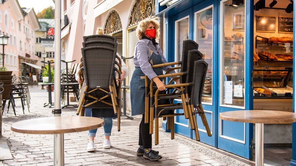 A shop owner carries seats as she closes her shop in the central pedestrian zone following the imposition of lockdown measures during the second wave of the coronavirus pandemic on October 20, 2020 in Berchtesgaden, Germany.