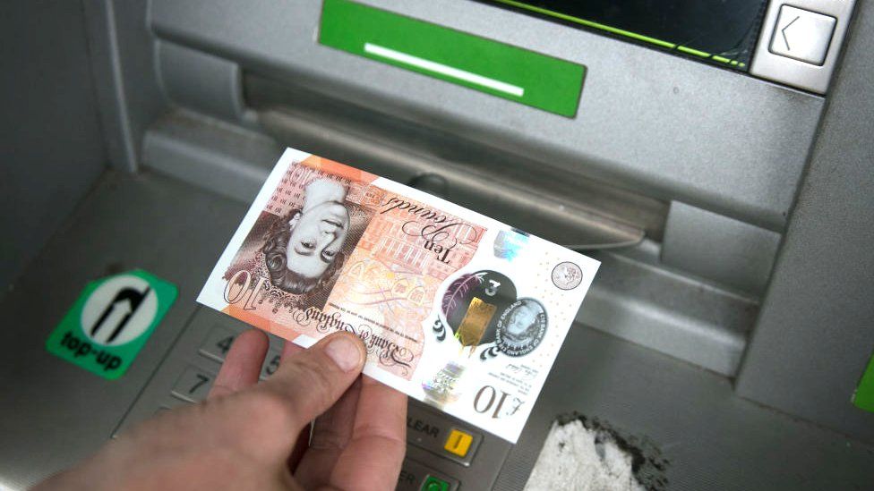 Ten pound note being withdrawn from a cash machine