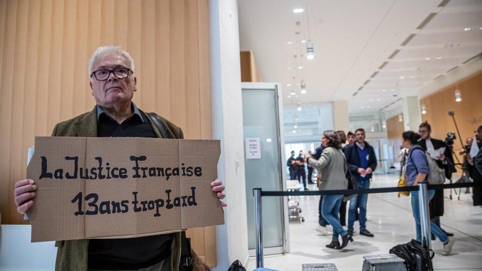 Winfried Schmidt, a relative of German victims holds a poster reading 'French Justice 13 years too late' in front of the courtroom on the first day of the nine-week Rio-Paris flight AF 447 trial at the Palais de Justice in Paris, France, 10 October 2022