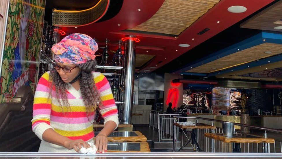 A woman cleaning a table in bar in Johannesburg, South Africa - August 2020