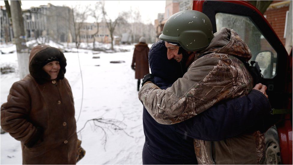 Пастор Олег приветствует местную жительницу объятиями в городе Угледар на востоке Украины