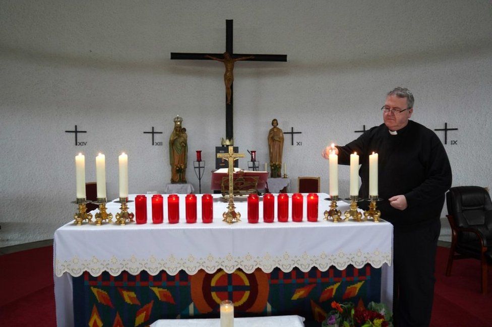 Отец Джон Джо Даффи зажигает свечи в церкви Святого Михаила в Крислоу в память о 10 жертвах