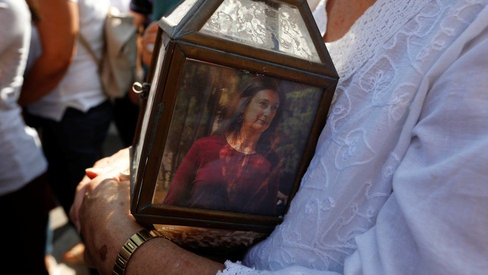 A woman holds a lantern with a picture of investigative journalist Daphne Caruana Galizia, who was assassinated in a car bomb attack, during a protest outside the law courts in Valletta, Malta, October 17 2017