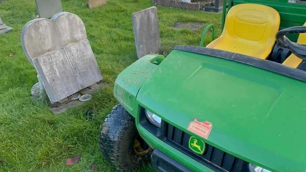 A green utility vehicle next to graves
