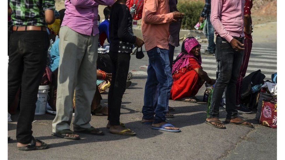 Migrant workers with their families rest at a roadside on their journey back to their hometowns in Uttar Pradesh and Bihar states