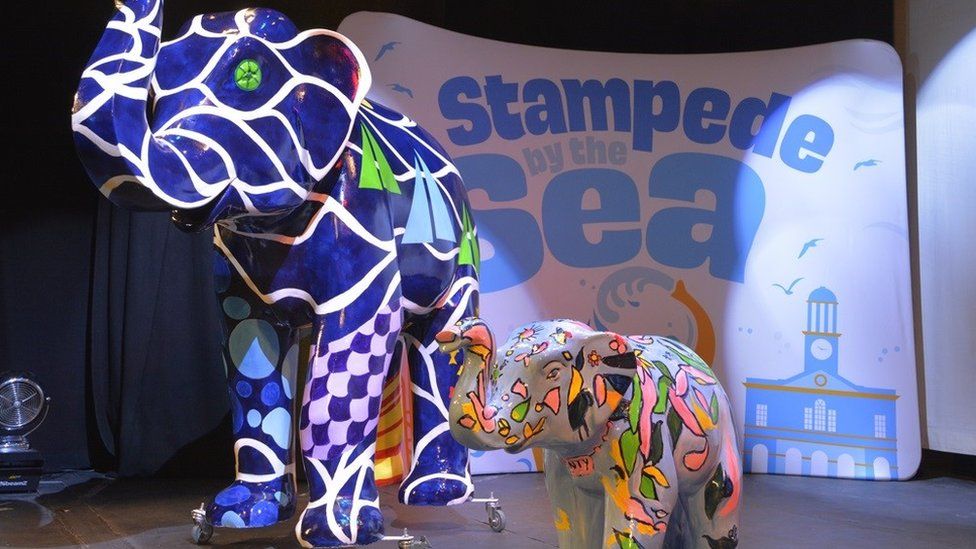One large and one small brightly painted elephant sculptures