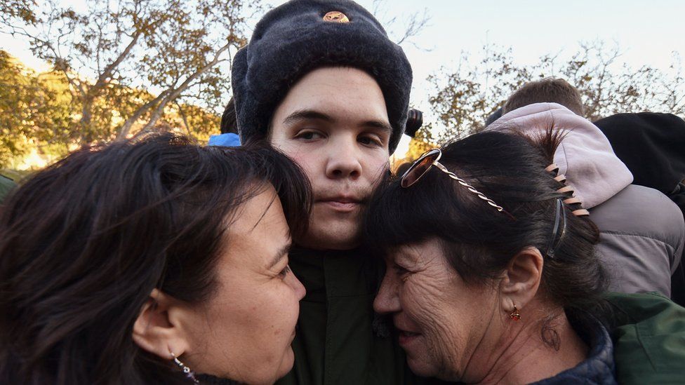 A Russian conscript bids farewell to his relatives before he leaves to serve in the army at a railway station in Sevastopol, Crimea